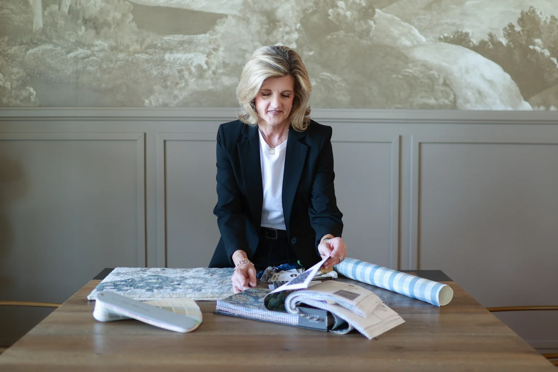 Jennifer Davenport reviewing design books and material samples at a table