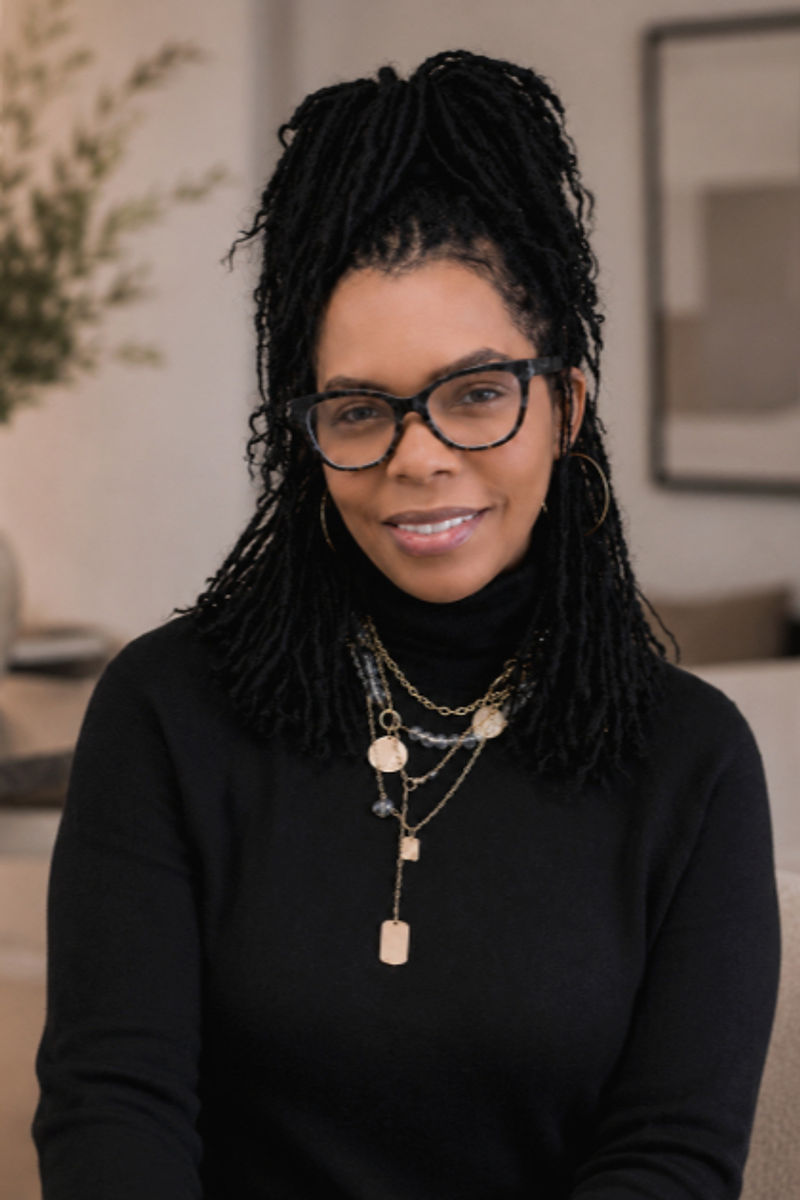 Kisha Bell smiling, with long locs and glasses